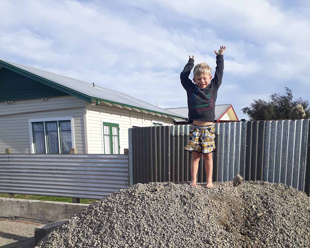 Young boy from Spiekerman family helping with the setup of Smile Caravans property by playing on pile of gravel