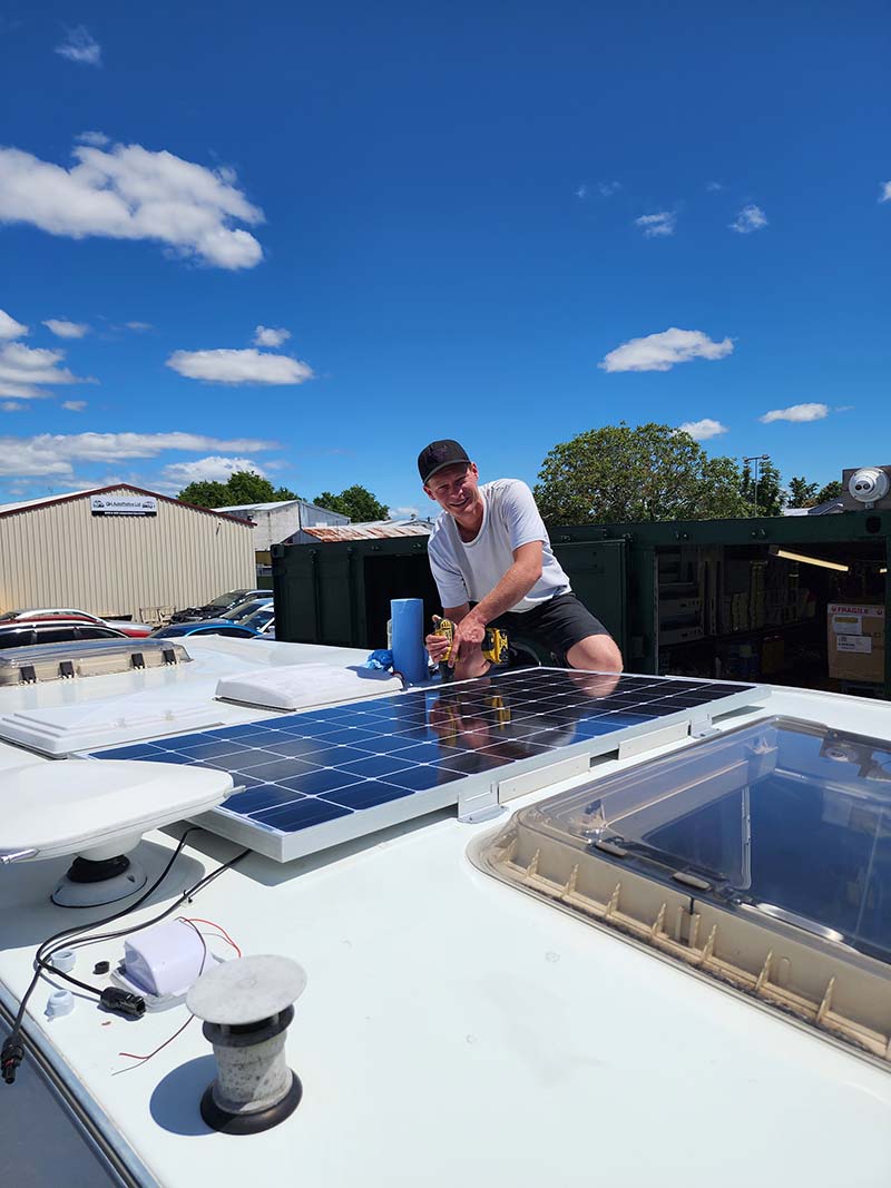 Andre from Smile Caravans installing a solar panel on caravan roof on sunny Hawkes Bay day